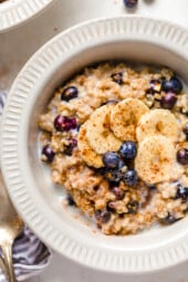 A bowl of steel cut oats topped with blueberries and bananas.